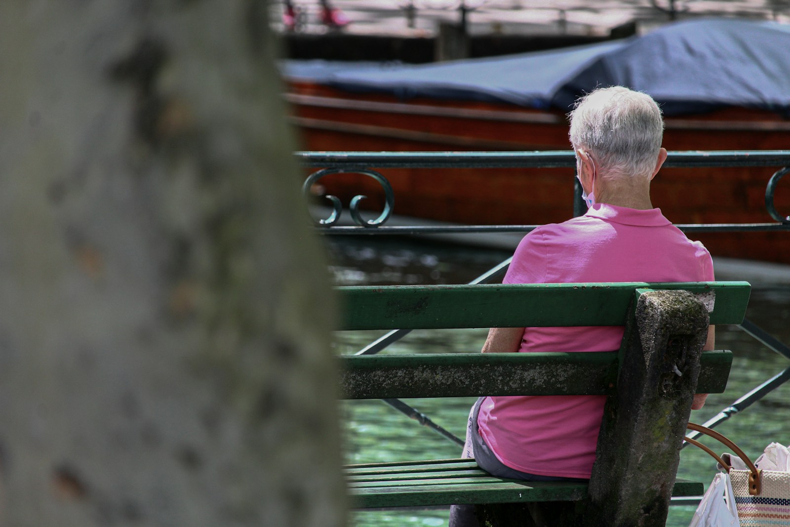 man in pink polo shirt sitting on brown wooden bench