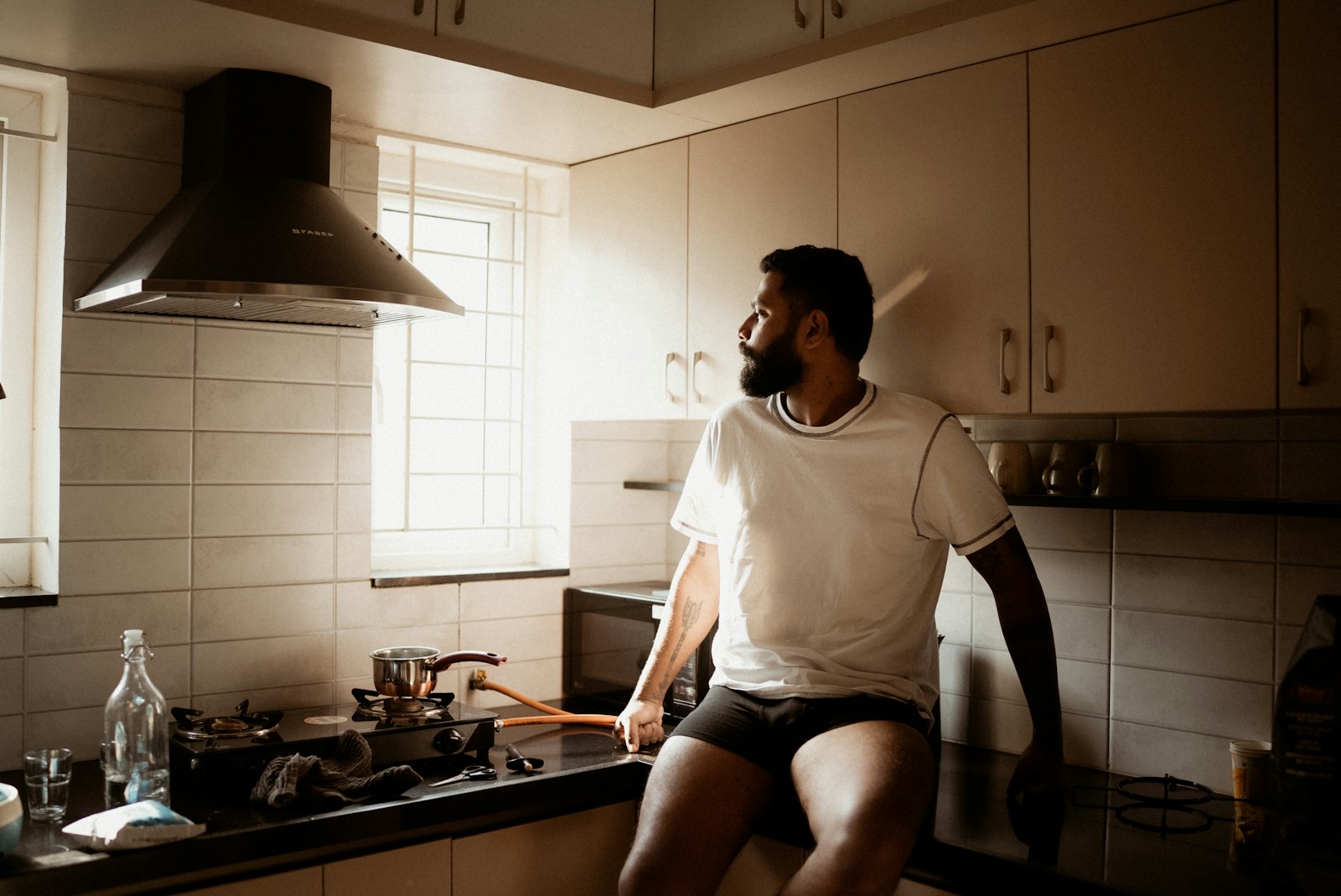 Man sits in kitchen looking out the window.