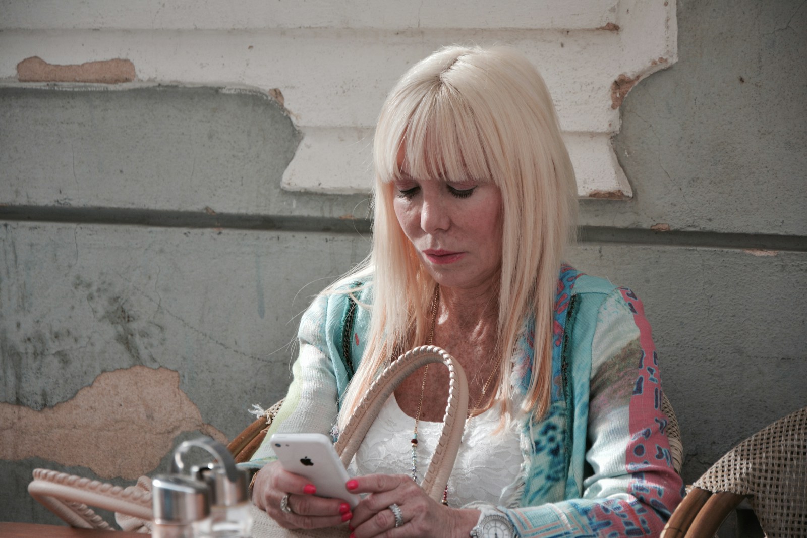 woman in green and white long sleeve shirt holding white smartphone