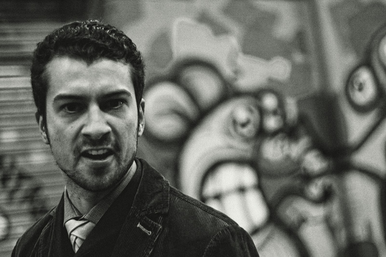 a black and white photo of a man in front of a graffiti wall