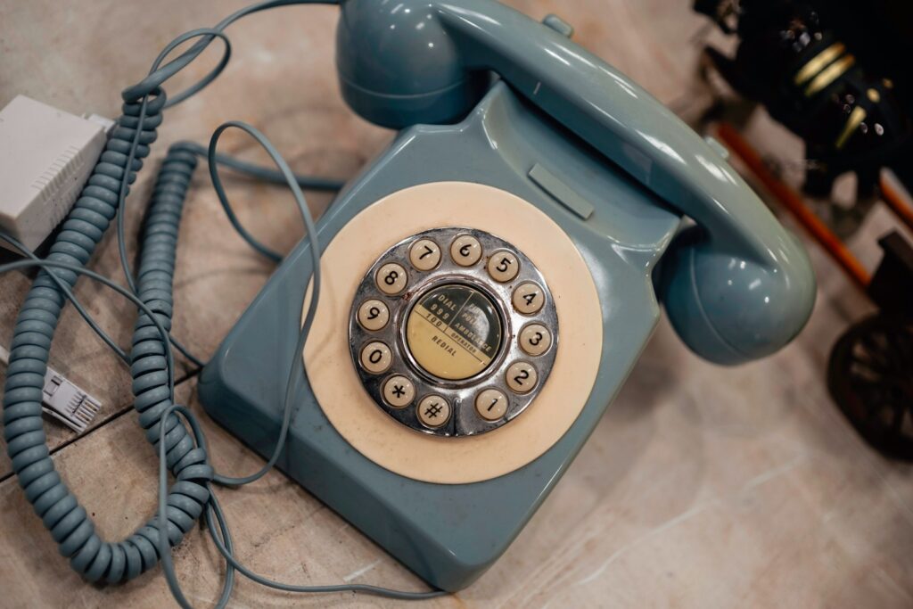 A vintage blue rotary dial telephone on a table.