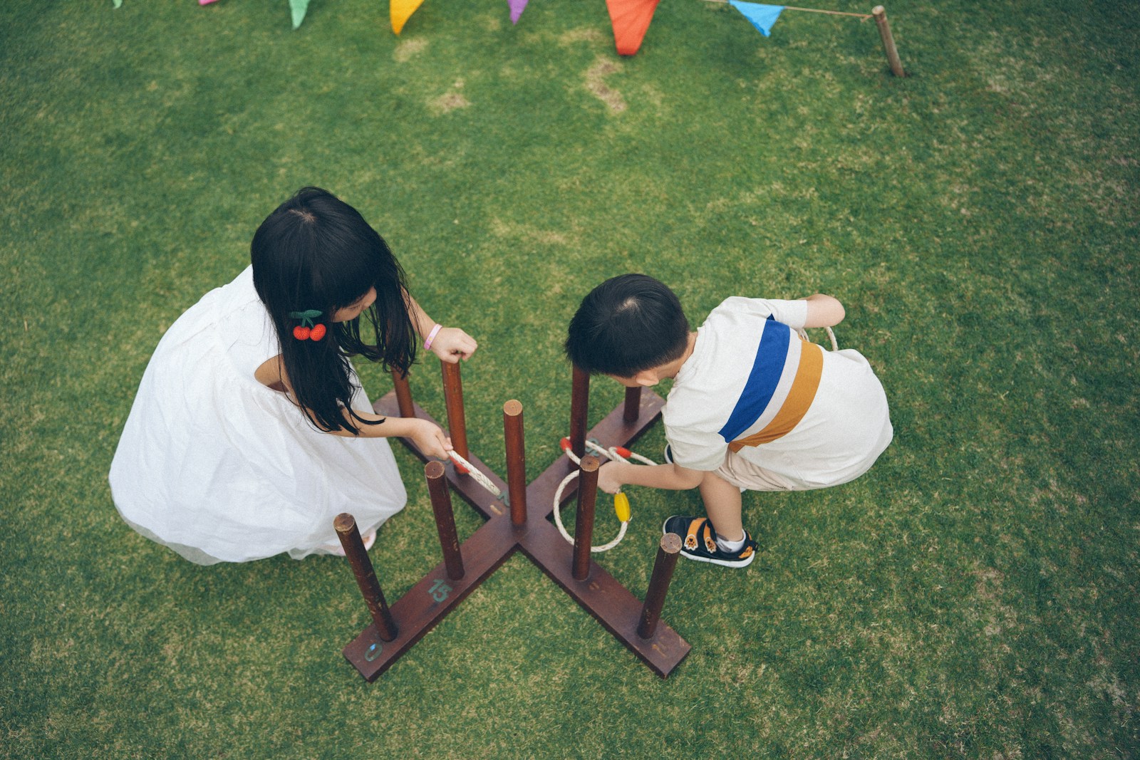 Children playing a ring toss game on grass.