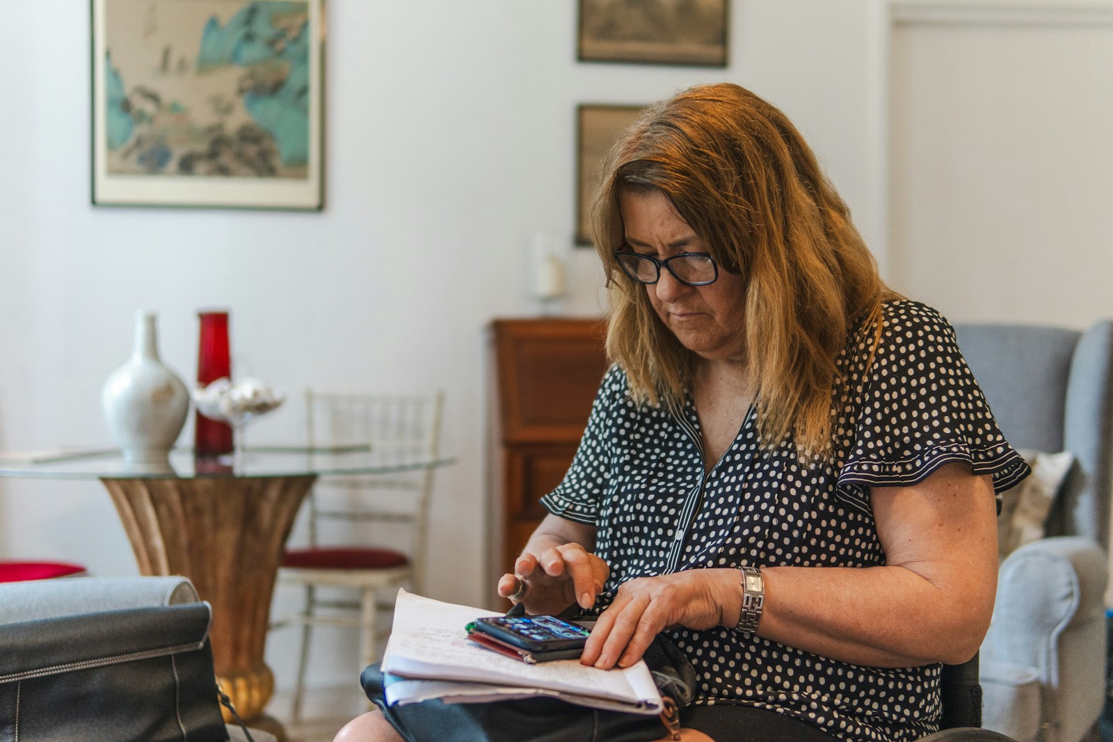 Woman using calculator with papers on table.