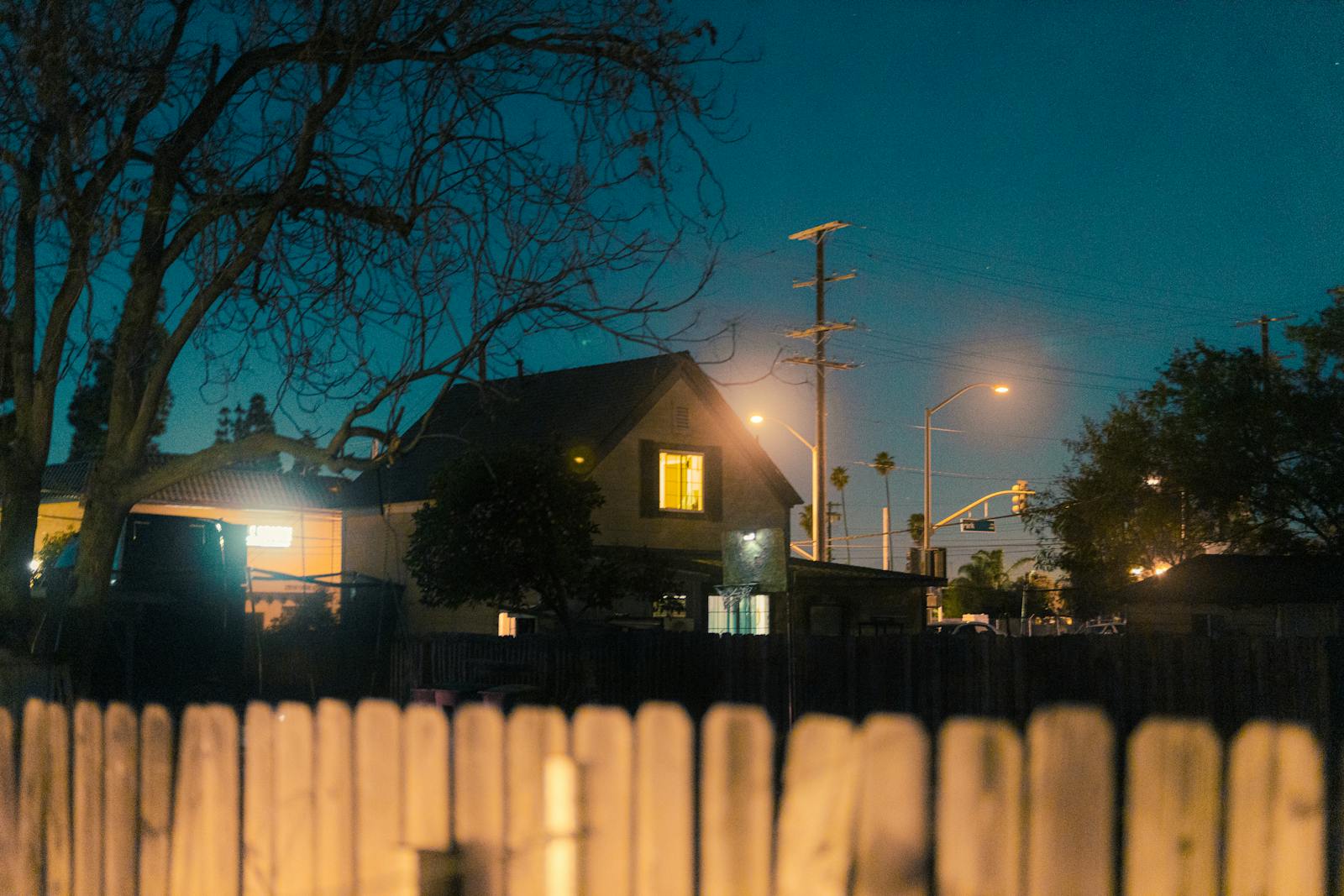 A serene nighttime view of a suburban area with houses illuminated by streetlights.