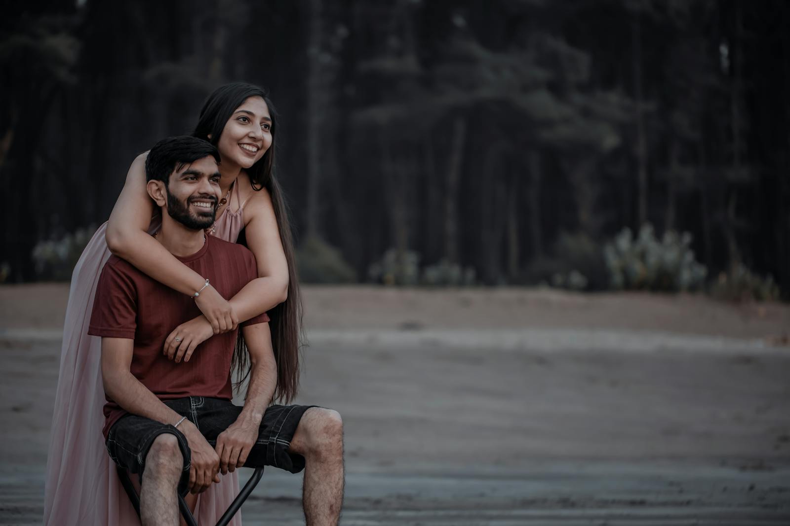 A joyful couple sitting together embracing in a serene forest environment.