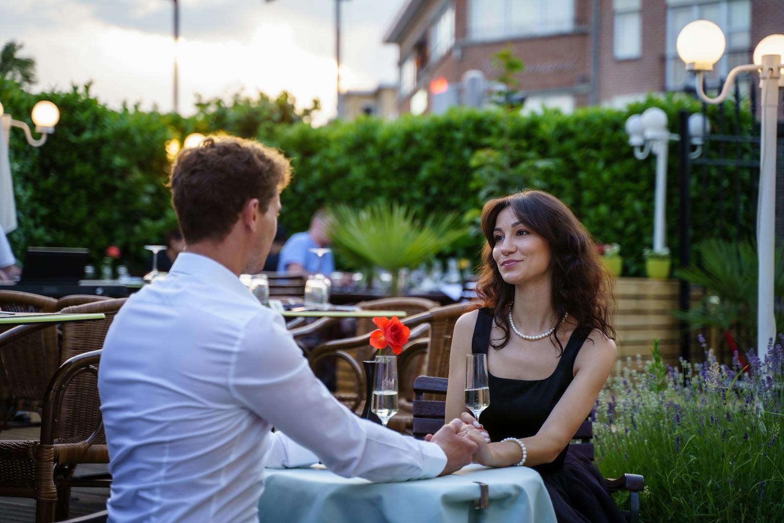 Couple enjoying a romantic dinner with drinks on an outdoor terrace.