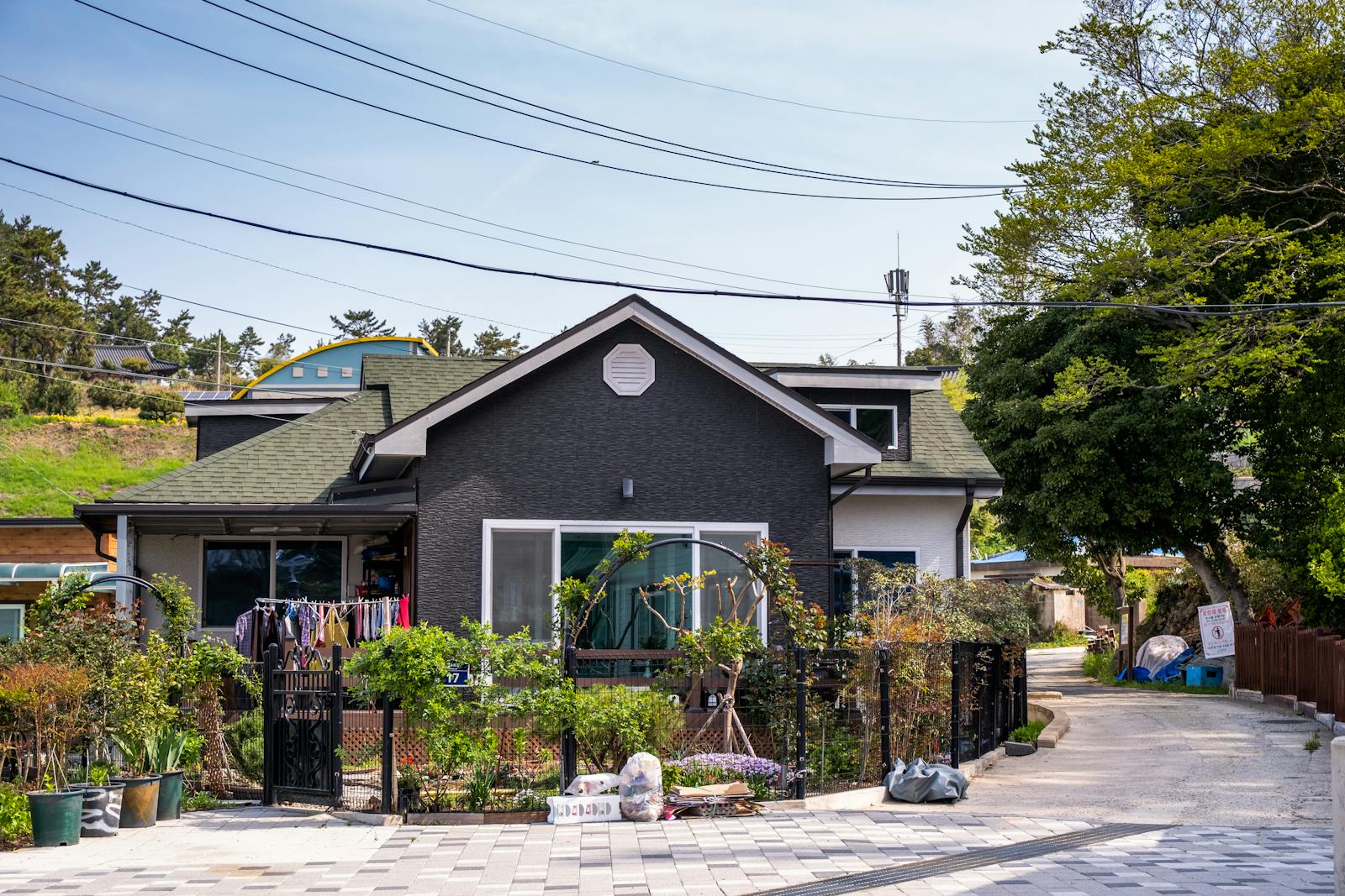 A charming suburban house with a lush front garden and laundry hanging outside on a sunny day.