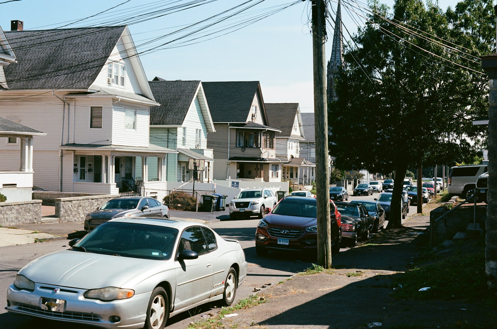 Cars parked on a street lined with houses.