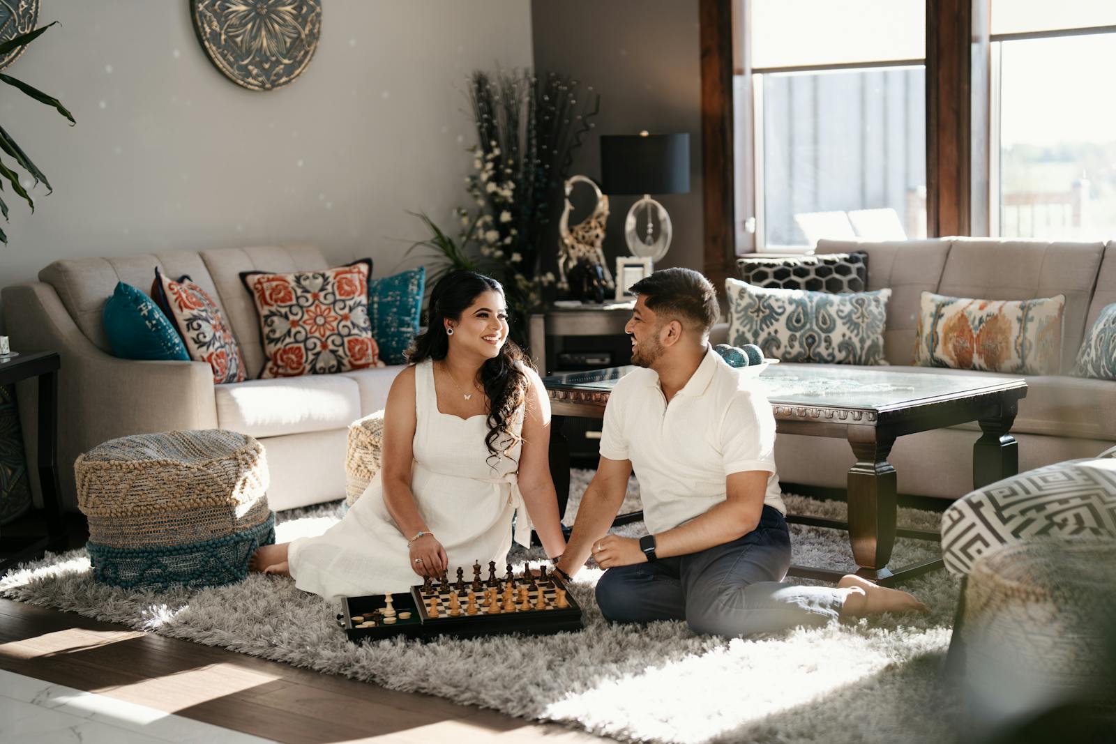 Engaged couple playing chess in a cozy living room in Toronto, embracing love and leisure.