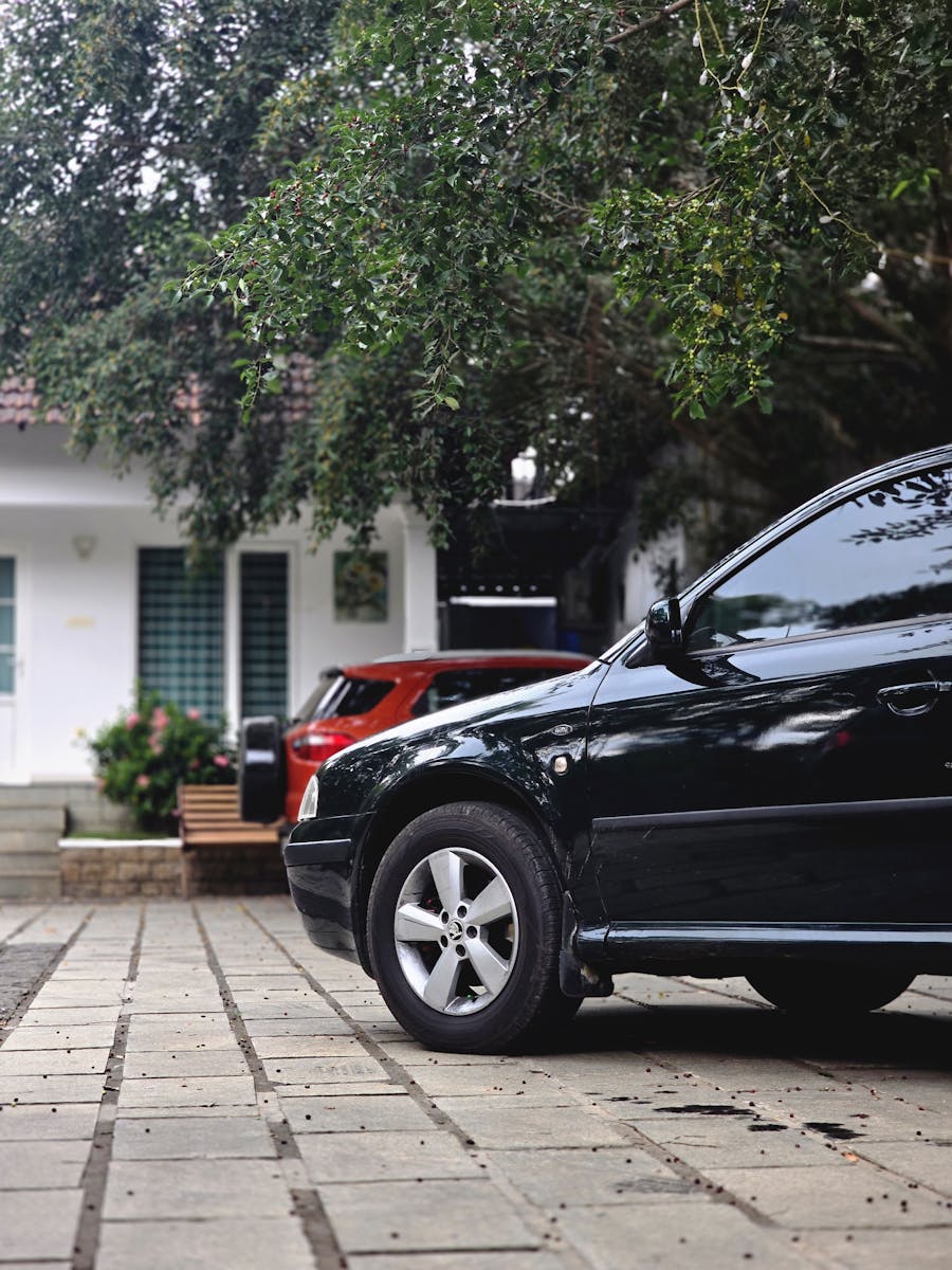 Close-up view of cars parked in a driveway with a modern house in the background.