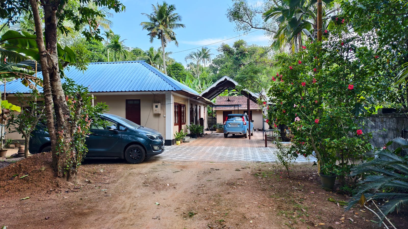 A peaceful rural home with a blue roof and vibrant garden in a tropical setting.