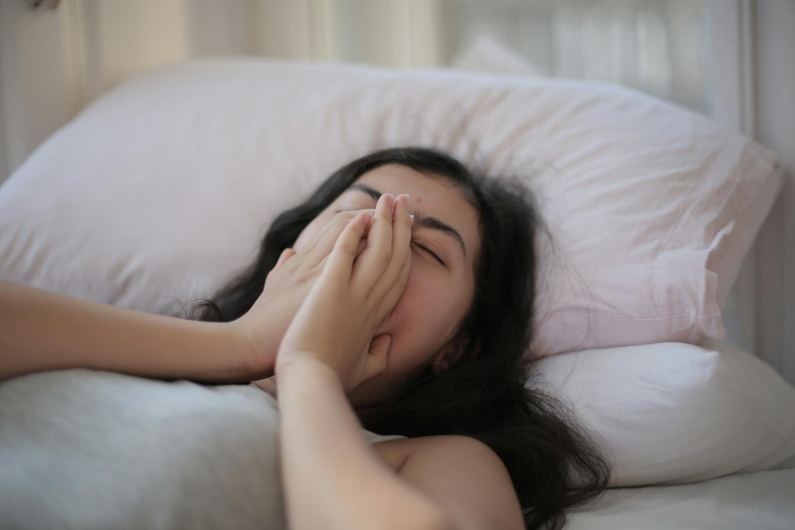 A serene scene of a woman resting in bed, displaying relaxation and comfort.