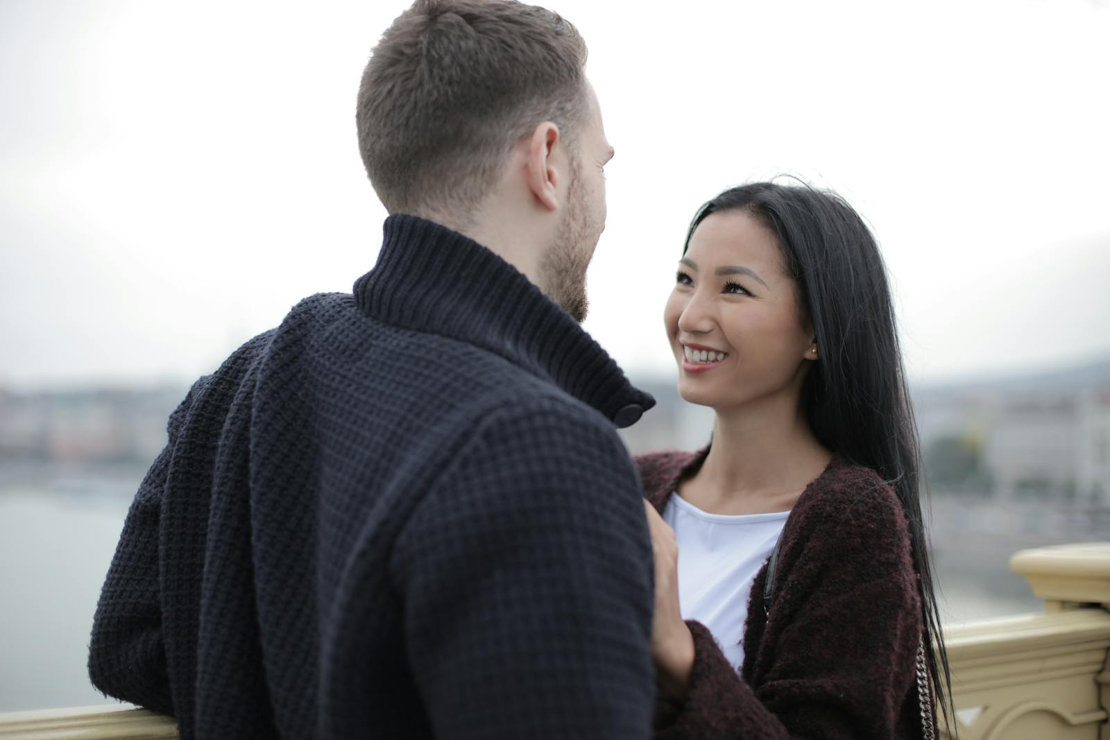 A happy couple smiling and enjoying a romantic moment together outdoors during the day.