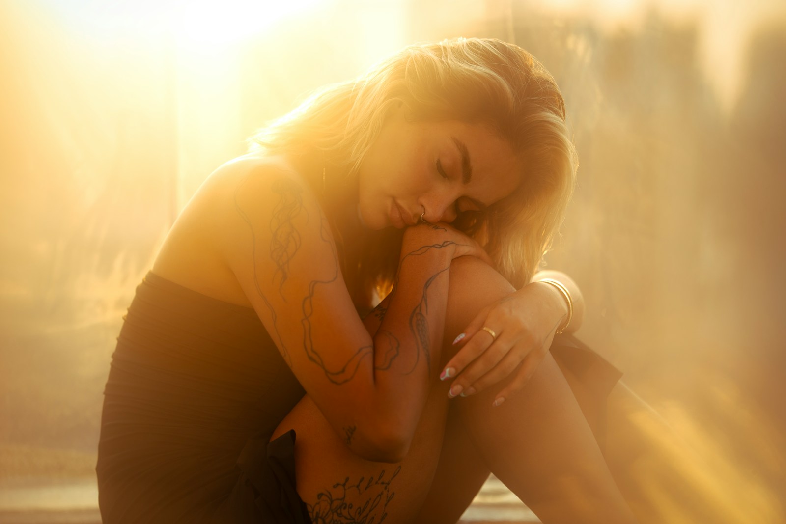 A woman sitting on a window sill with her hands on her face