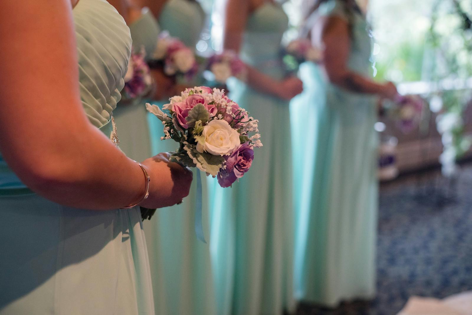 Side view of crop unrecognizable women in stylish dresses with bright bridal bouquets on wedding day
