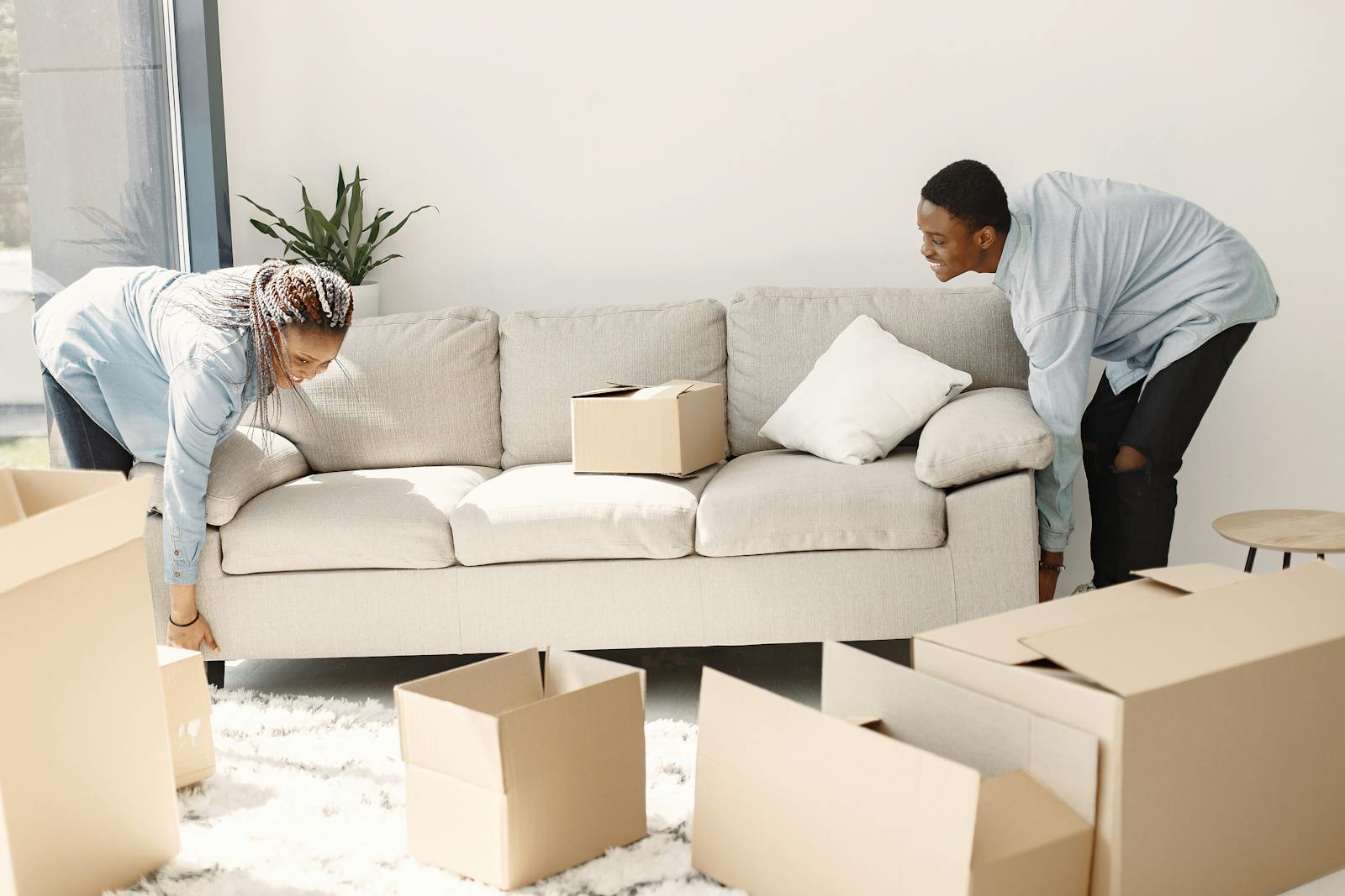 Happy couple setting up a sofa in their new home surrounded by moving boxes.