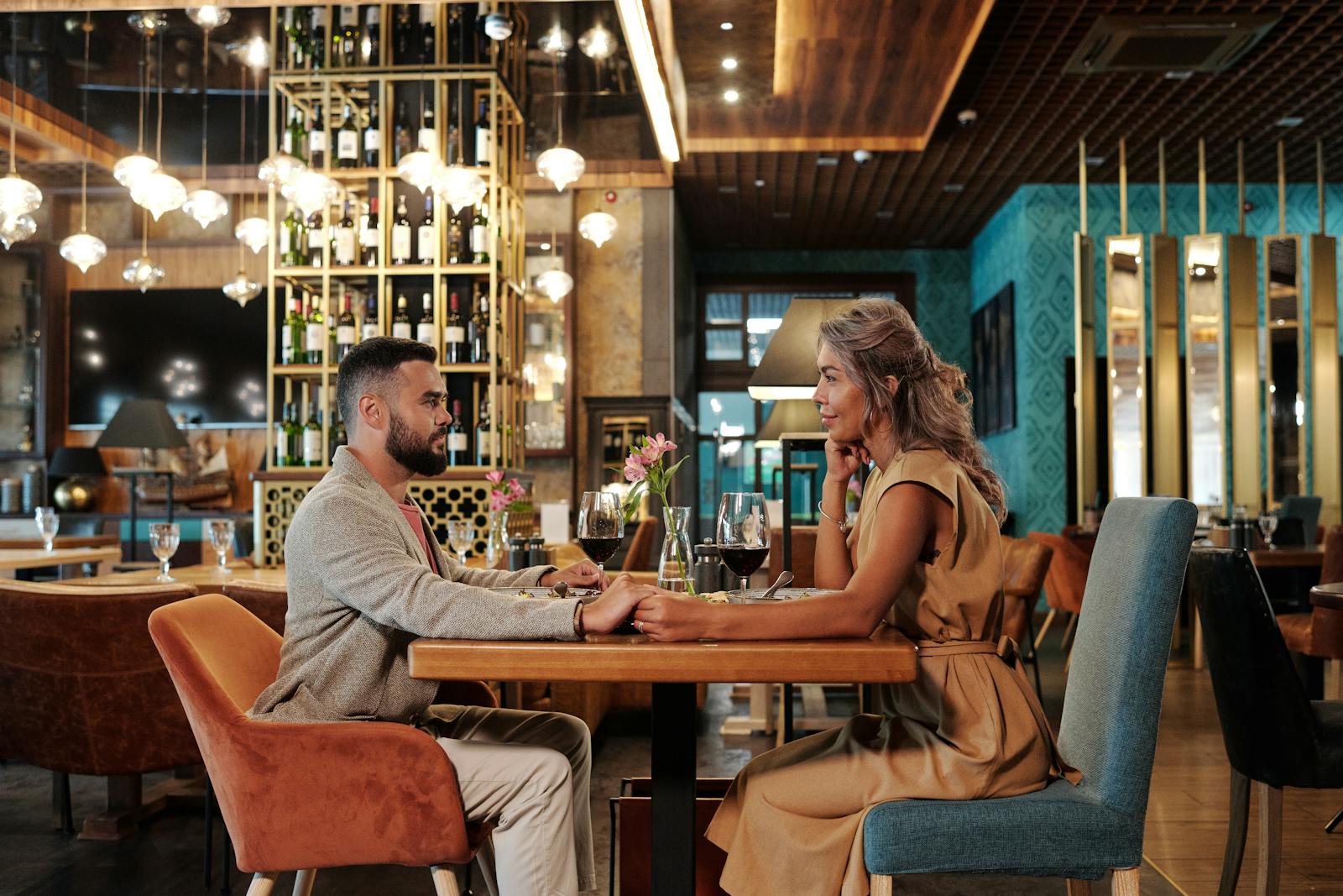 Couple enjoying a romantic dinner with wine in an elegant restaurant setting, creating a warm atmosphere.