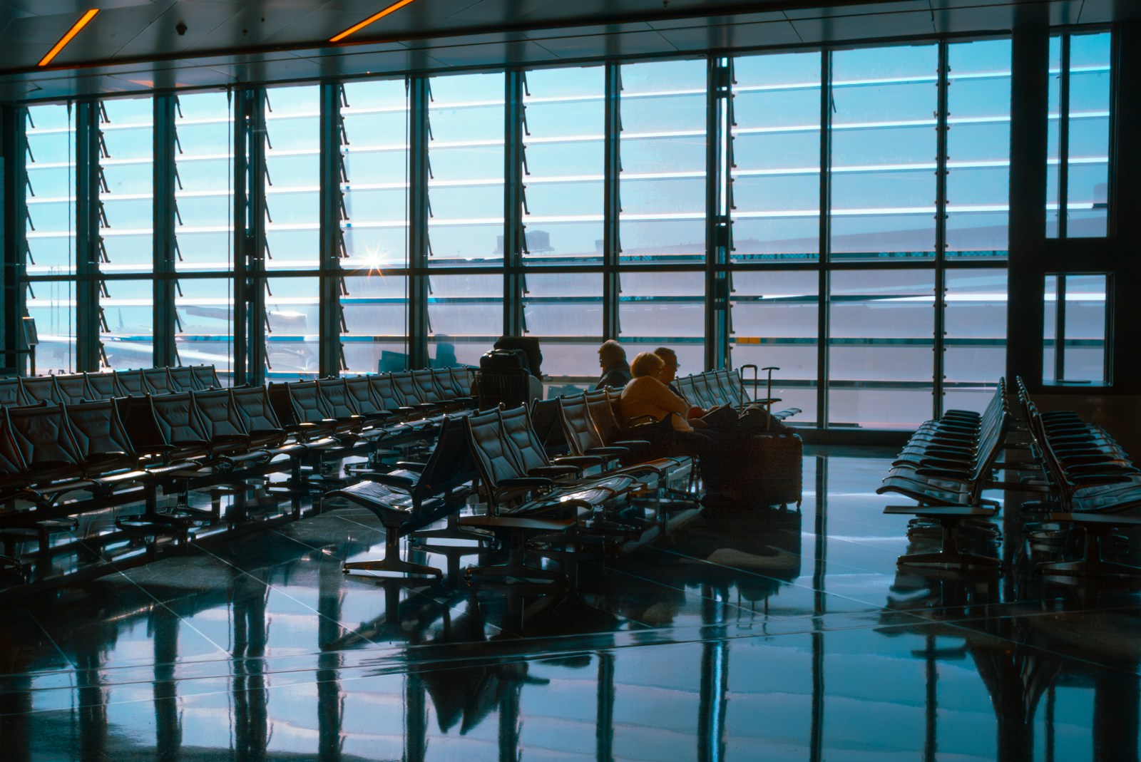 People sit in a bright and spacious airport terminal.