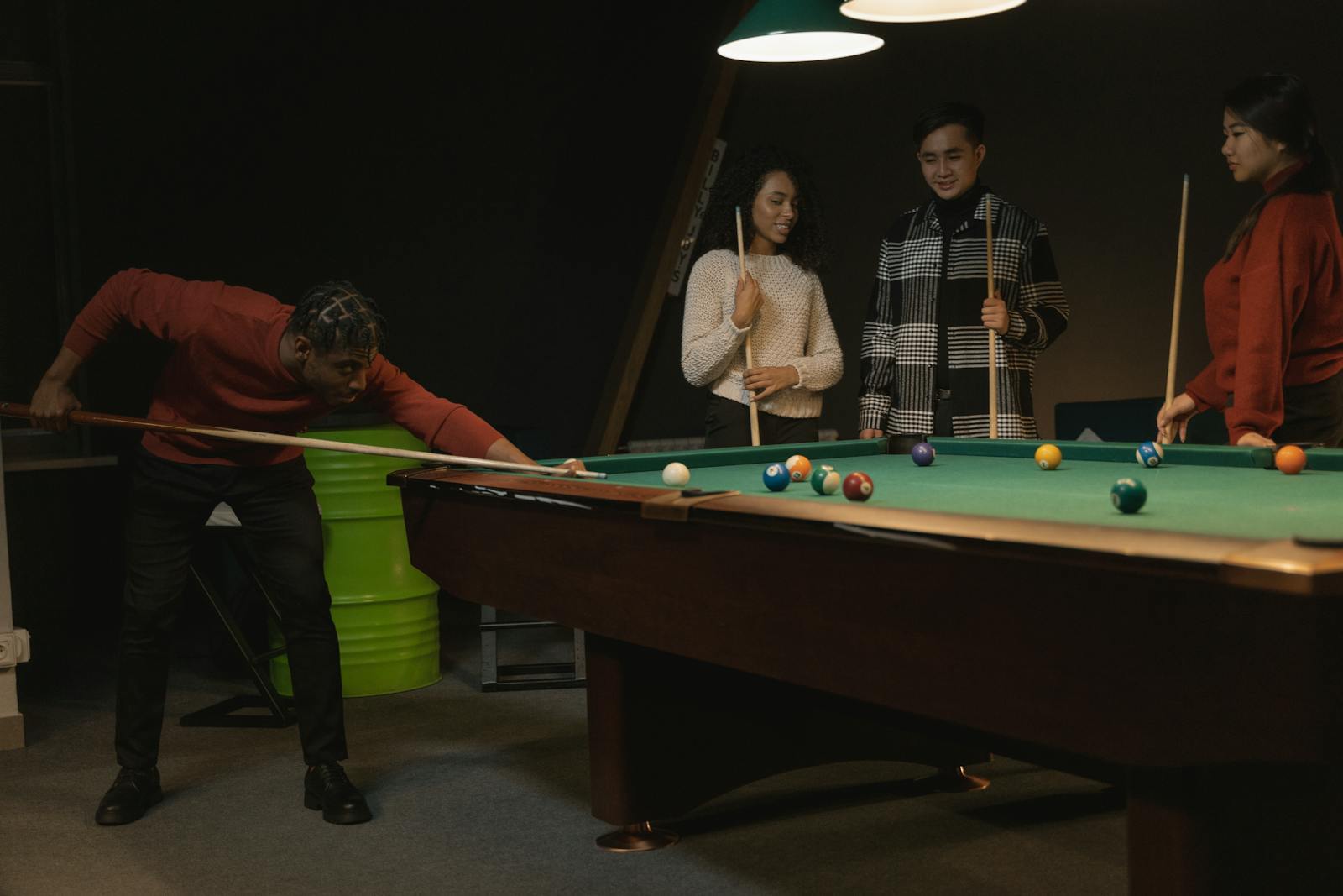 Diverse group enjoying a game of billiards in a cozy indoor setting, showcasing leisure and friendship.