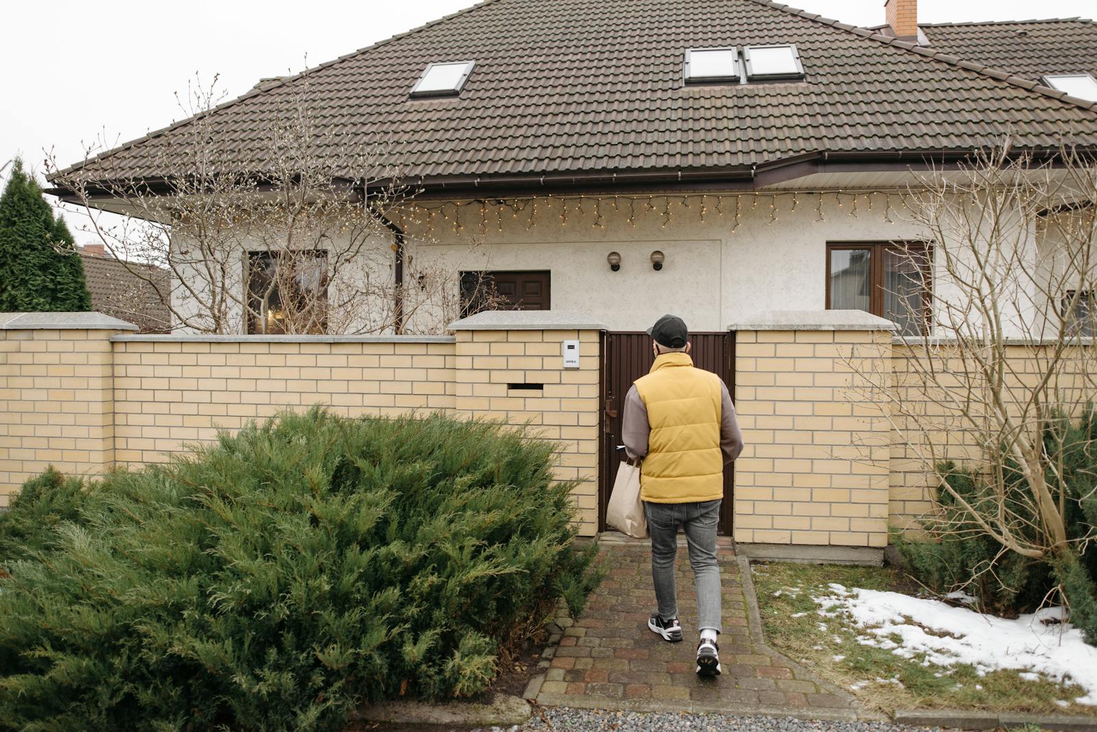 A delivery person brings a package to a suburban house on a winter day.