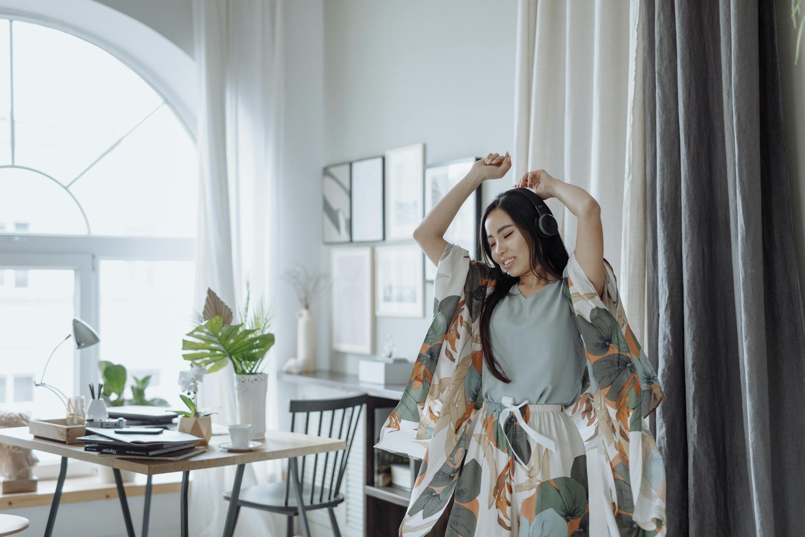 A cheerful woman dances to music in a stylish living room, expressing joy.