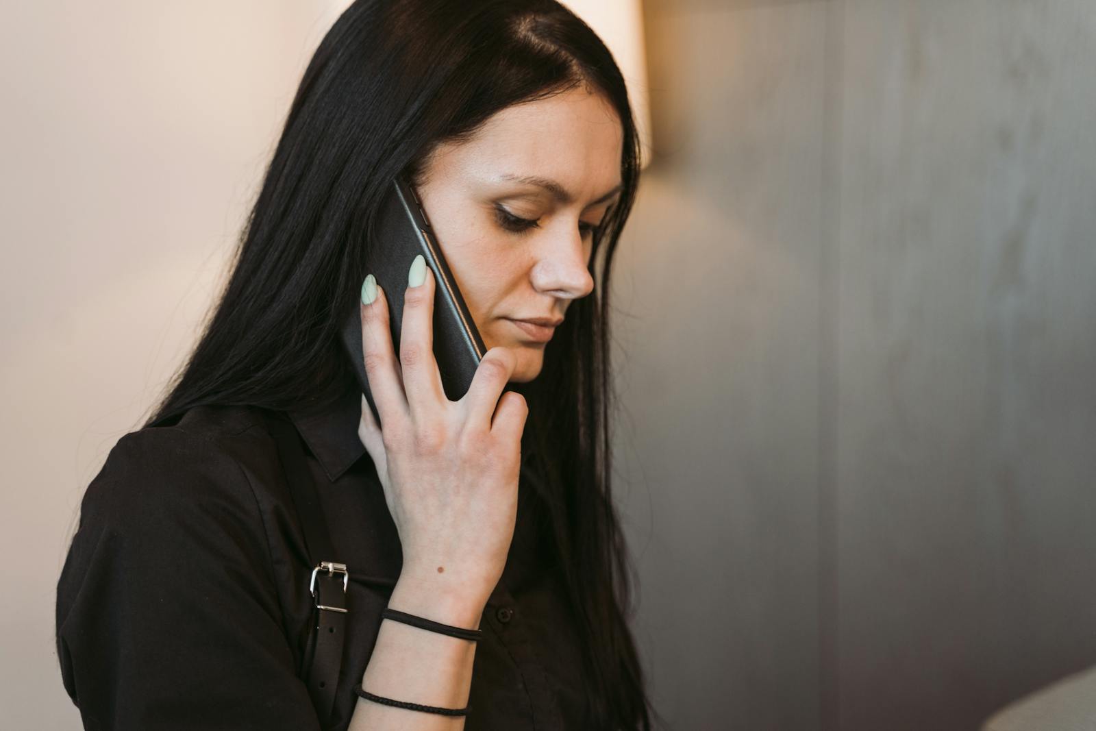Side view of a woman with long hair holding a mobile phone, engaged in conversation.