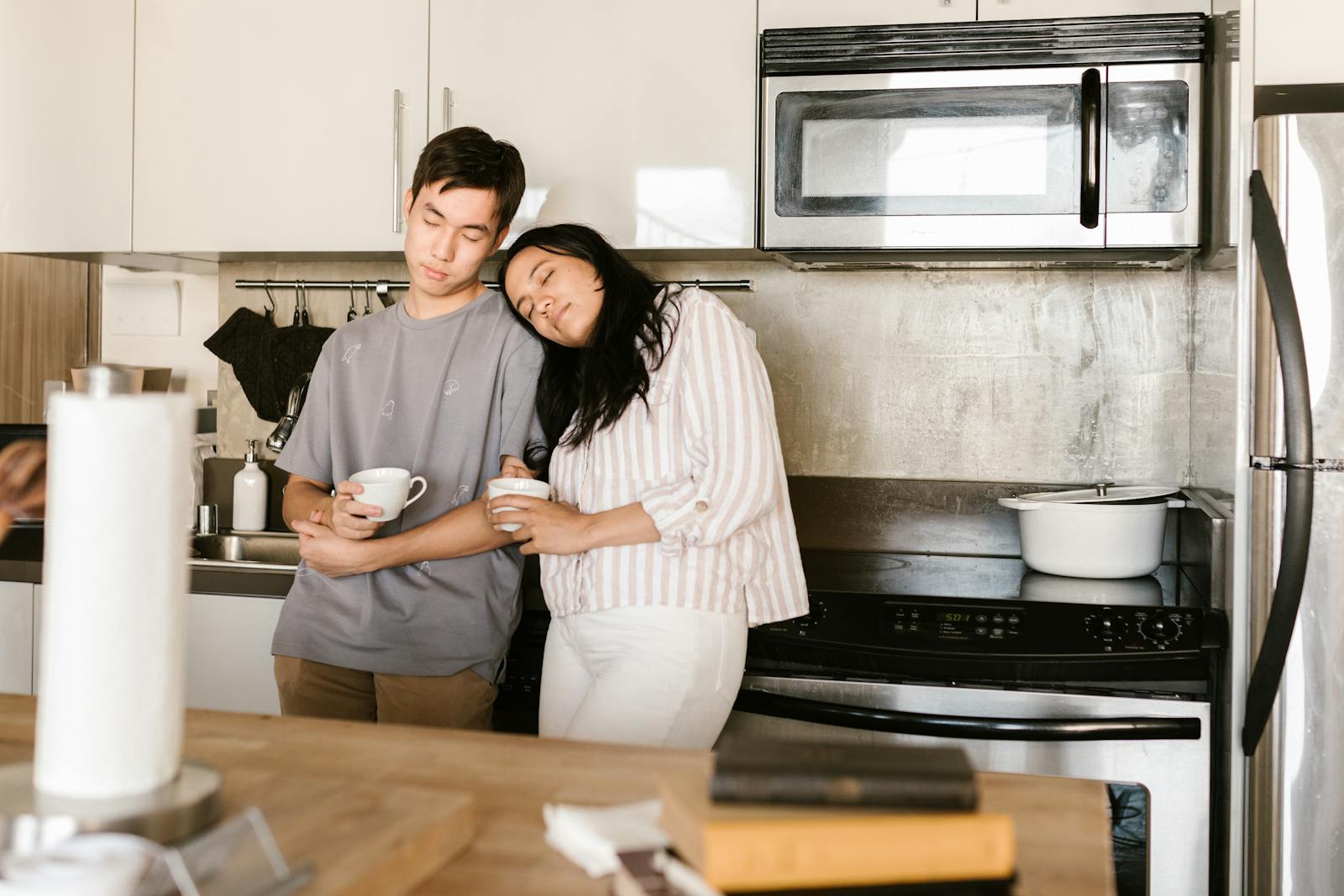 A couple enjoys a relaxing morning with coffee in their kitchen, reflecting comfort and connection.