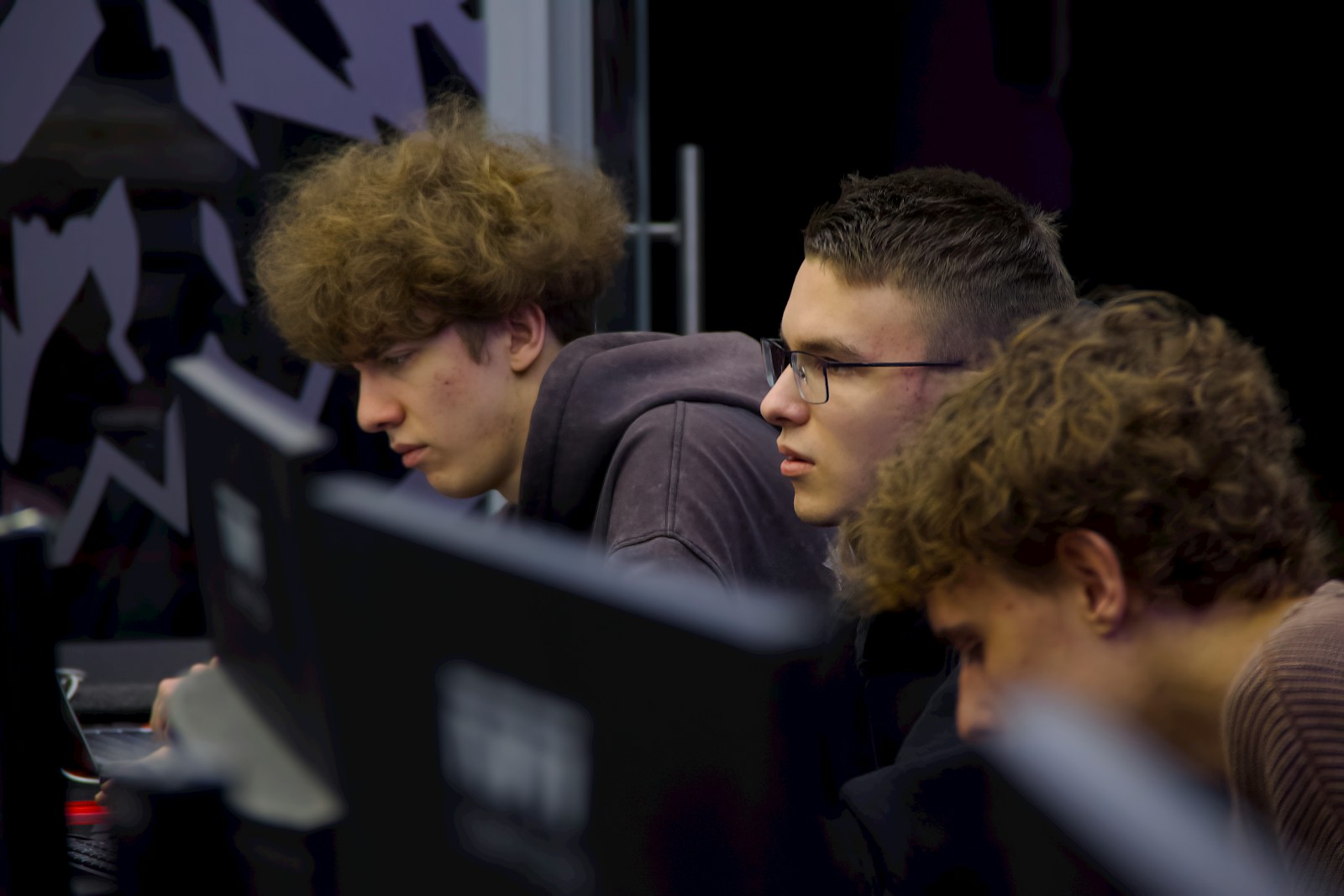 Three young men focused on computer screens