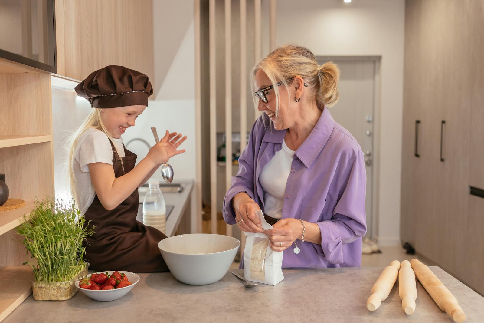 Cheerful grandma and granddaughter bonding while baking in the kitchen, sharing joyful moments.