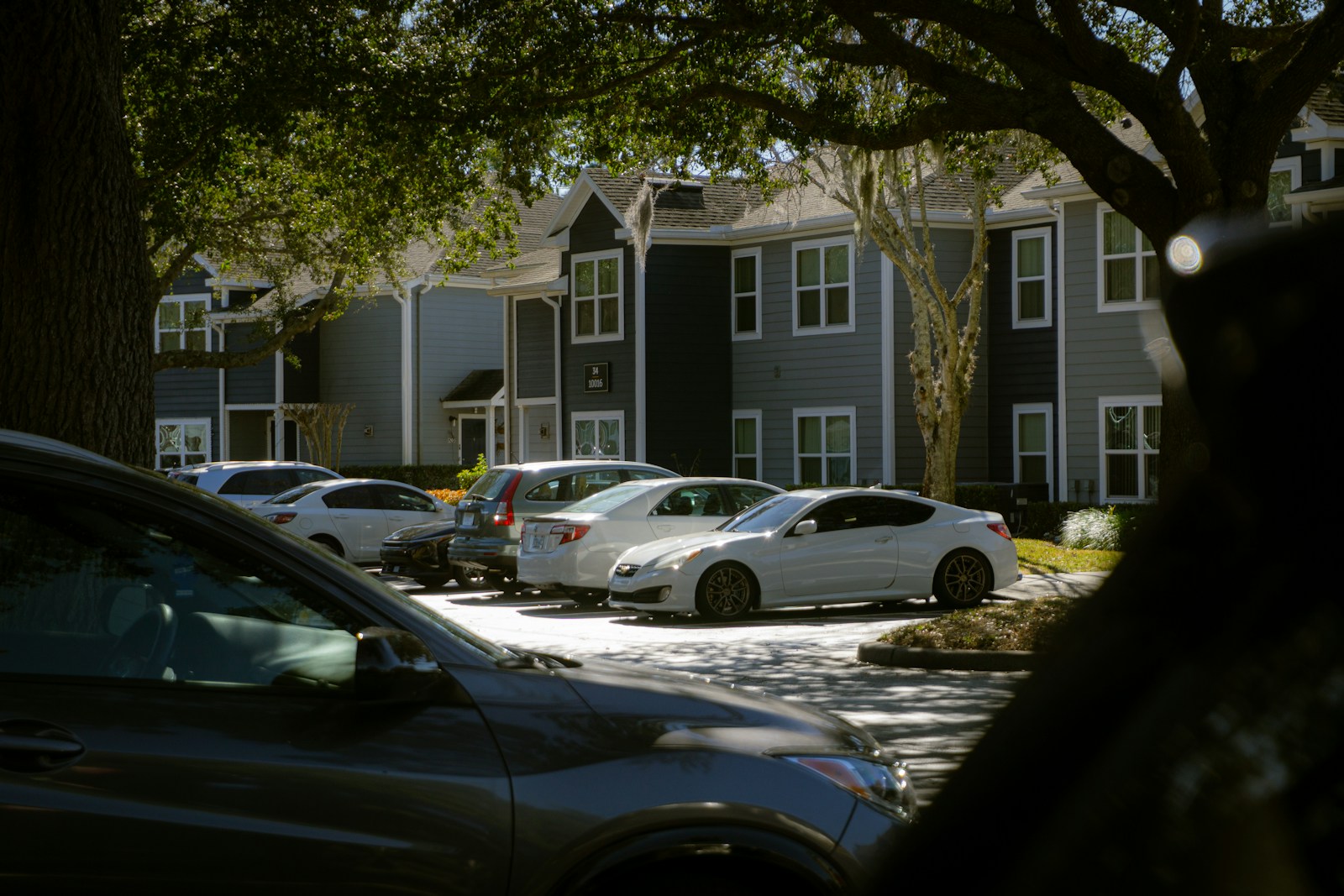 Apartment buildings with parked cars in a lot.