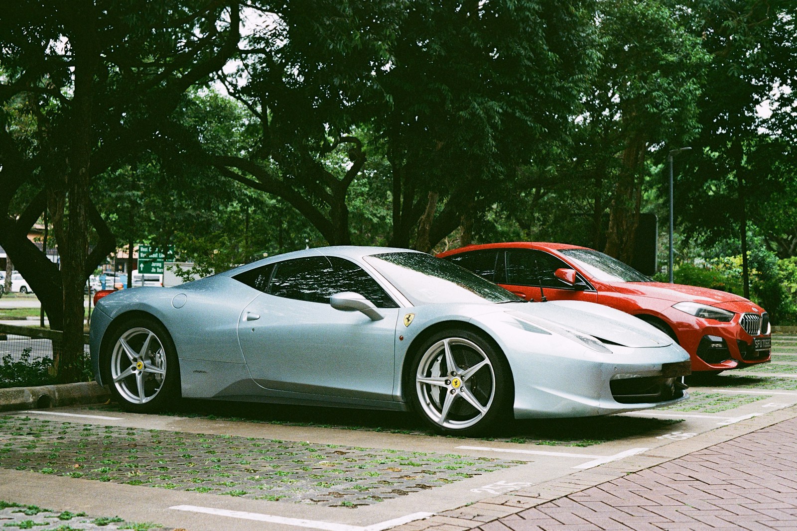 A silver ferrari parked next to a red car.