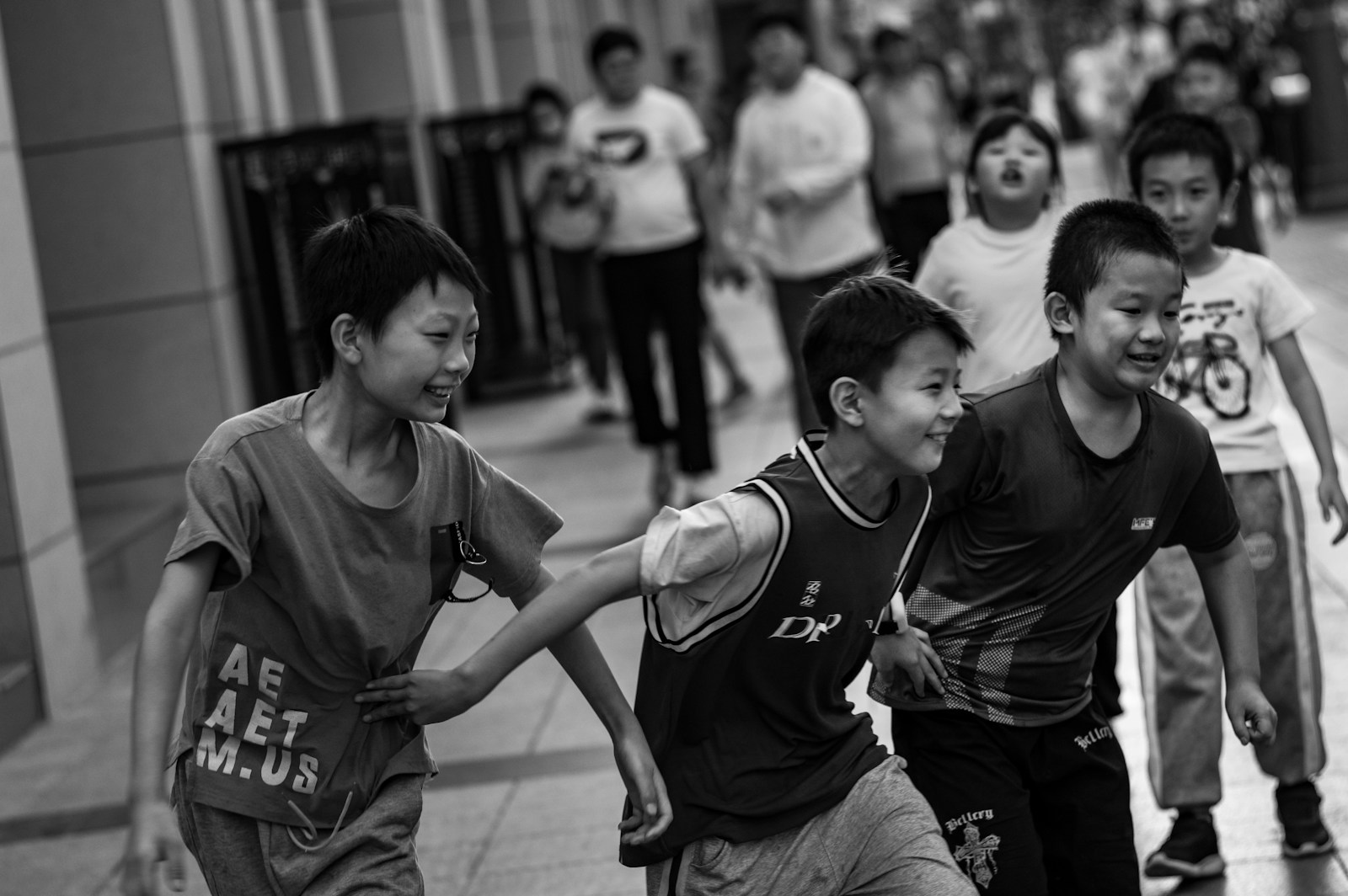 A group of young boys running down a sidewalk