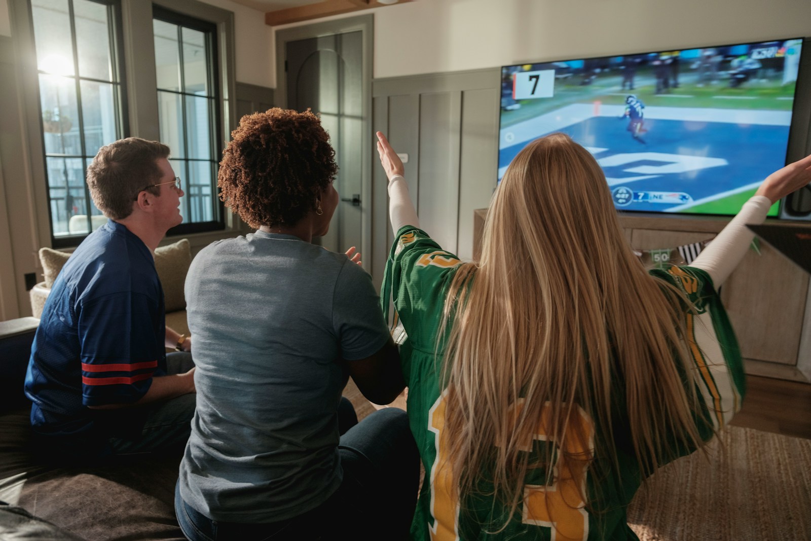 Friends watching a sports game on television together at home.