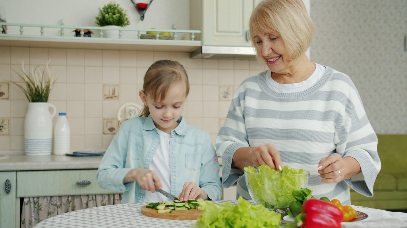 Grandmother and granddaughter preparing food in the kitchen.