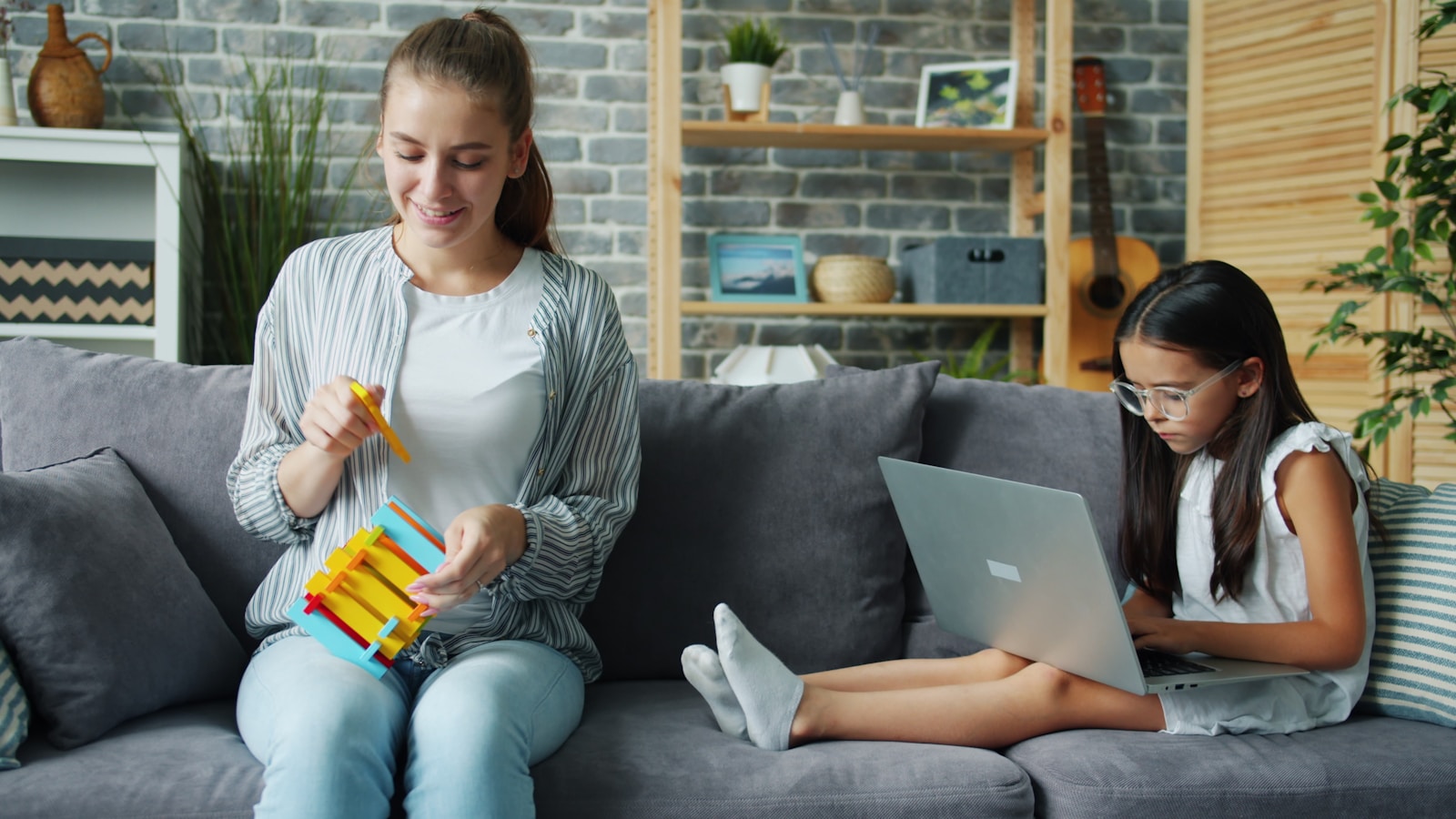 Woman and girl on couch with laptop and toy.