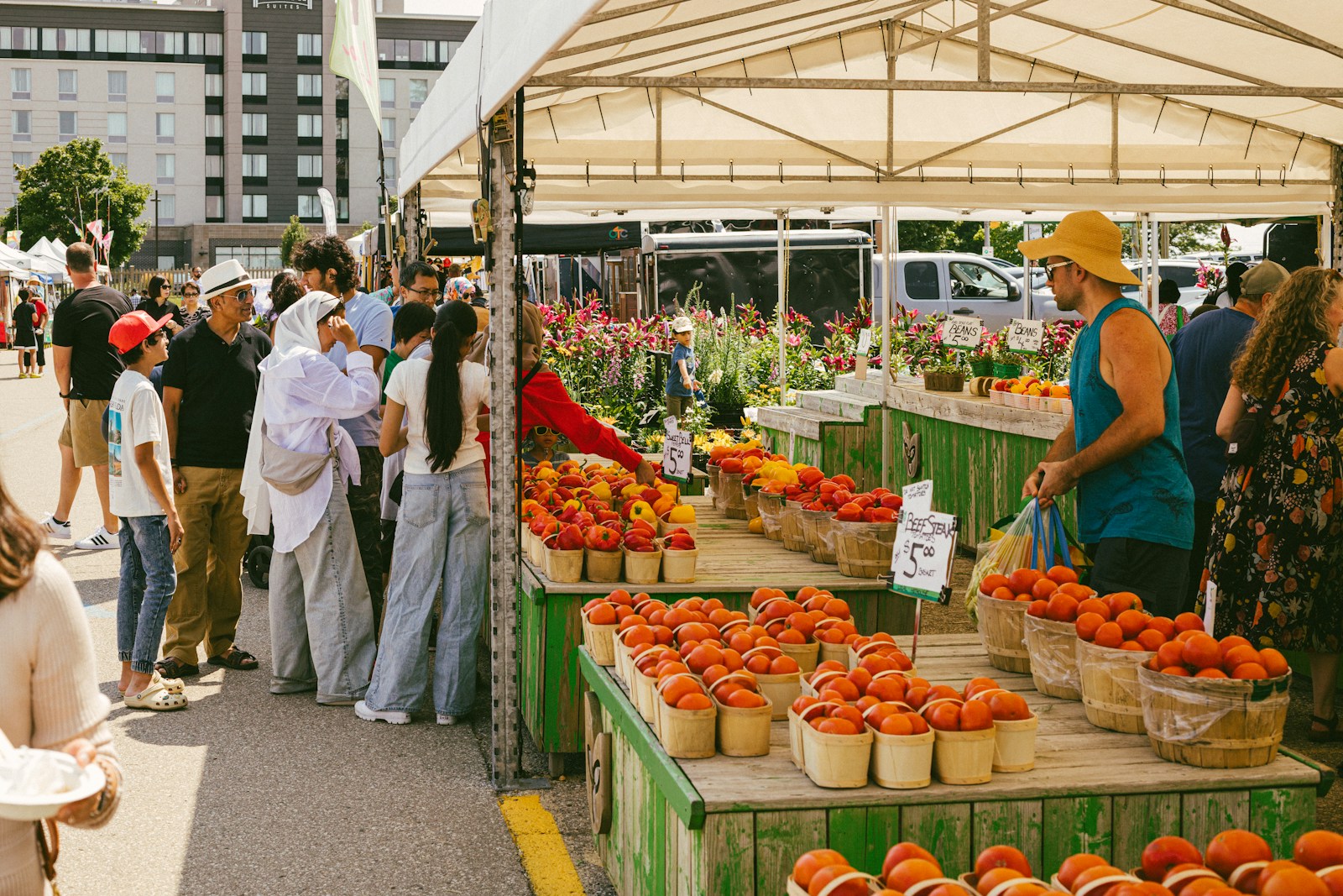 People shopping at an outdoor farmers market with fresh produce.