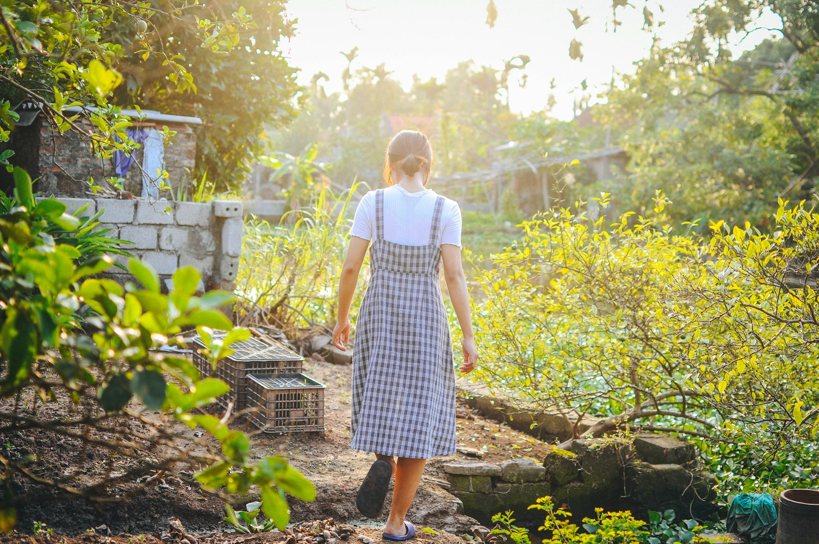 a woman in a dress walking through a garden