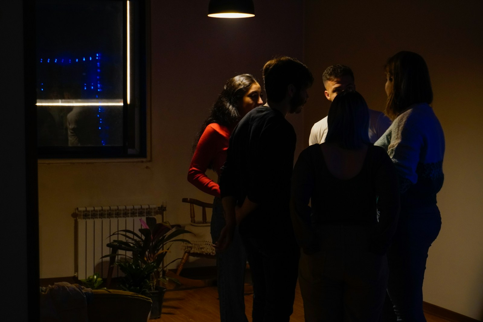 Friends gather in a dimly lit room.