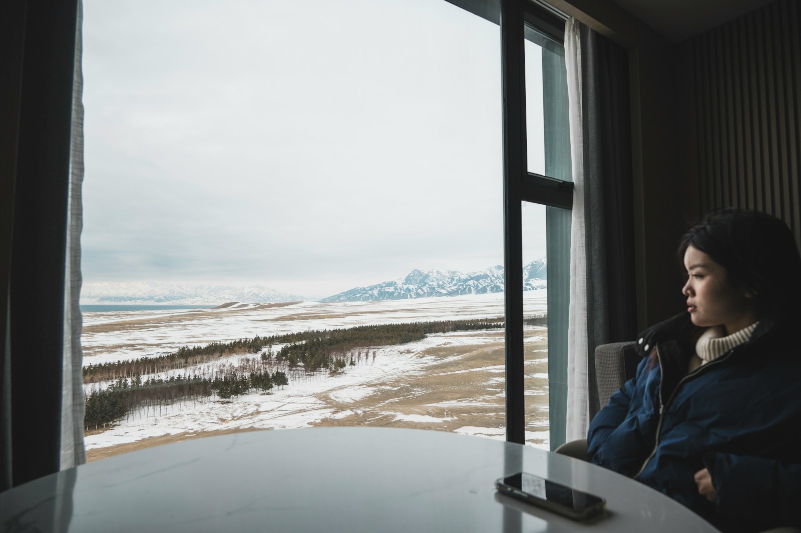 Woman looking out a window at a snowy landscape