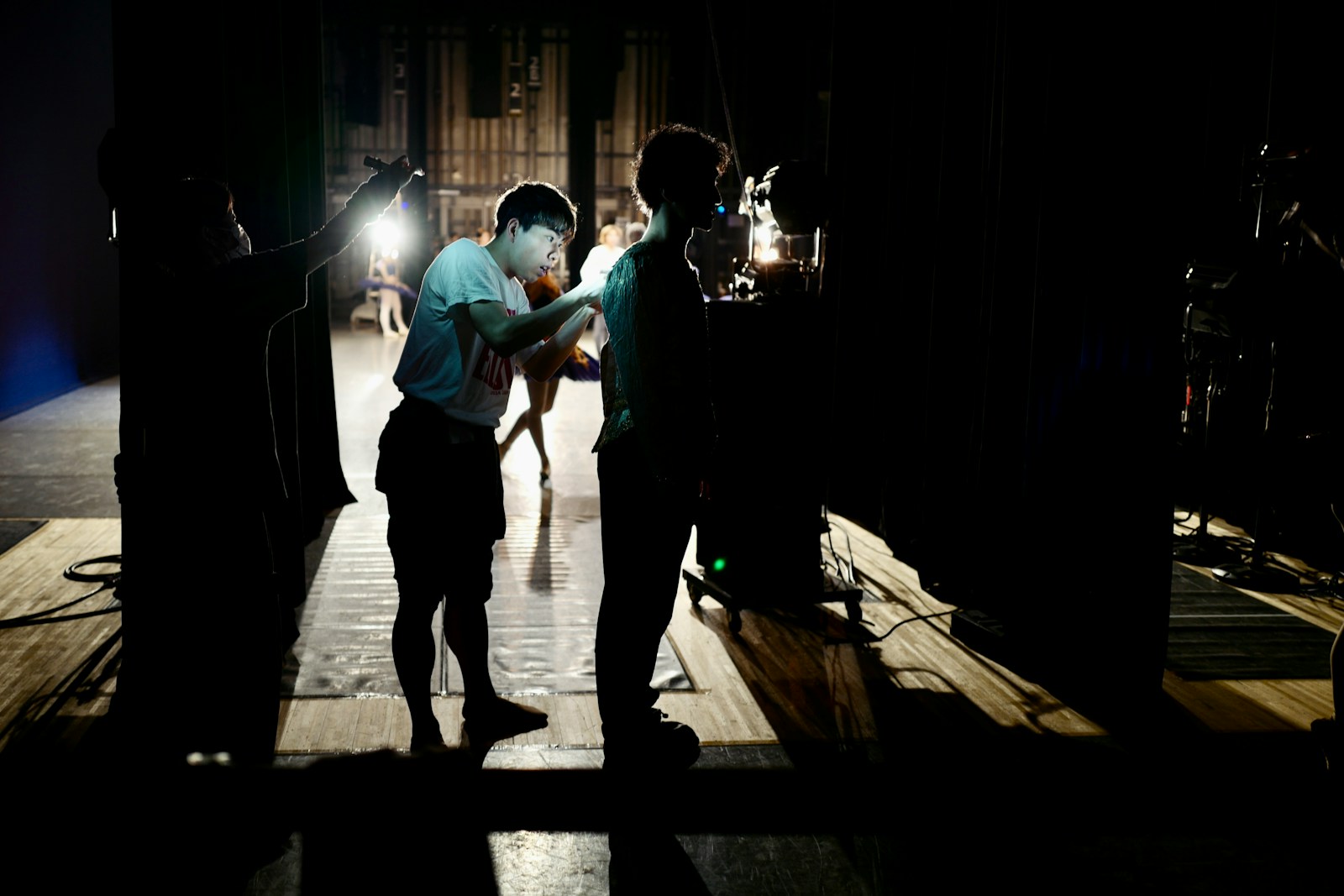 Stagehands working behind the scenes on a dimly lit stage.