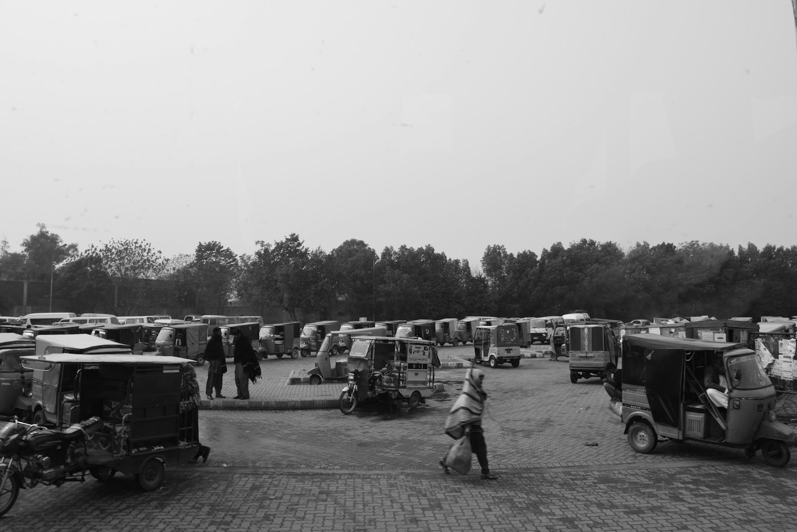 Many auto rickshaws parked in an open area.