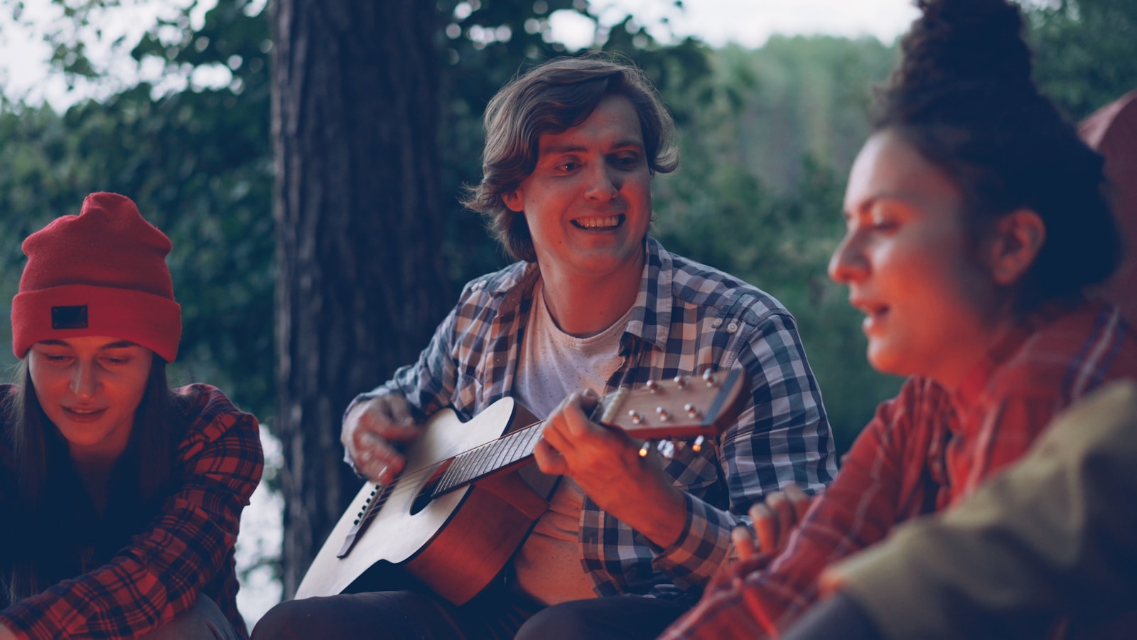 Friends gathered around campfire playing guitar and singing