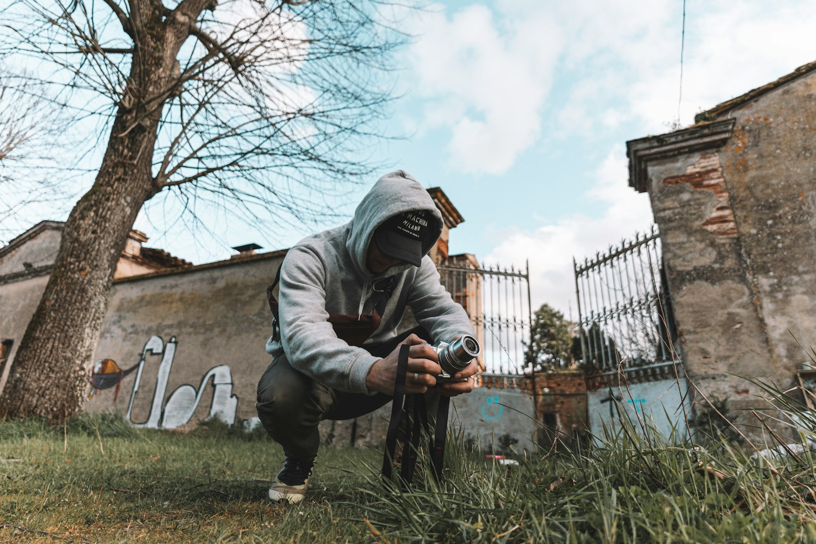 man in gray hoodie and black pants holding black and white labeled bottle