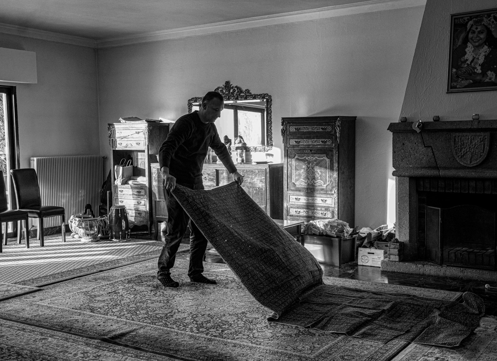 a black and white photo of a man moving a rug