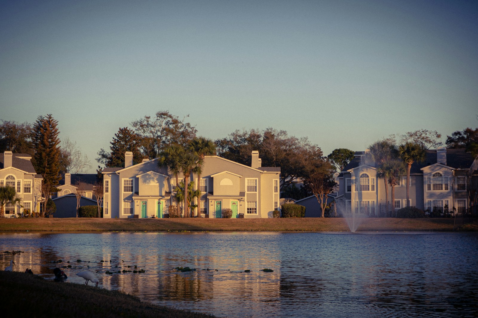 Apartment buildings reflected in a calm lake at sunset