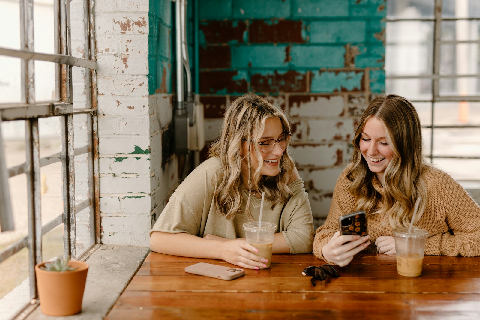two women sitting at a table looking at a cell phone