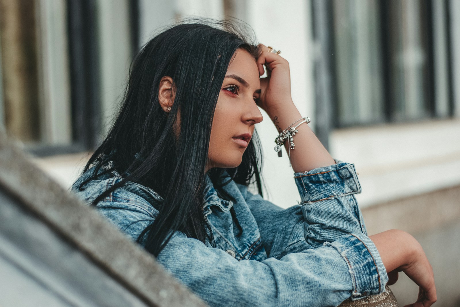 a woman with long black hair leaning against a wall