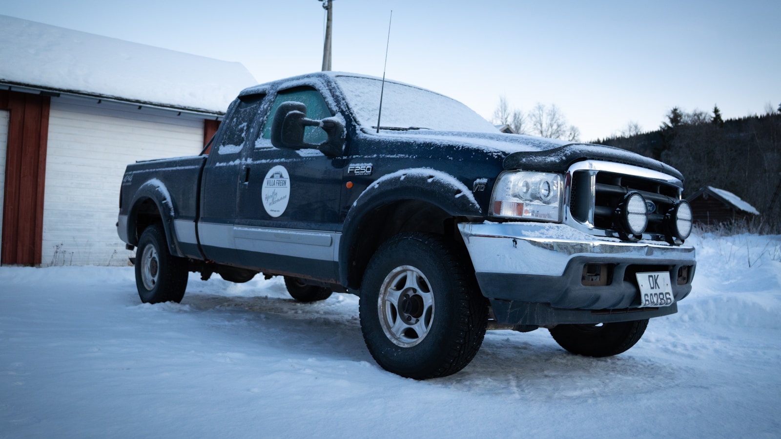 A truck parked in the snow in front of a building