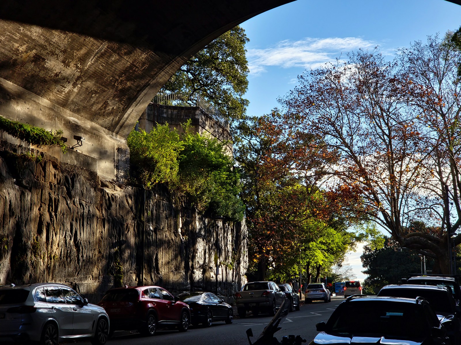 a city street filled with lots of traffic under a bridge