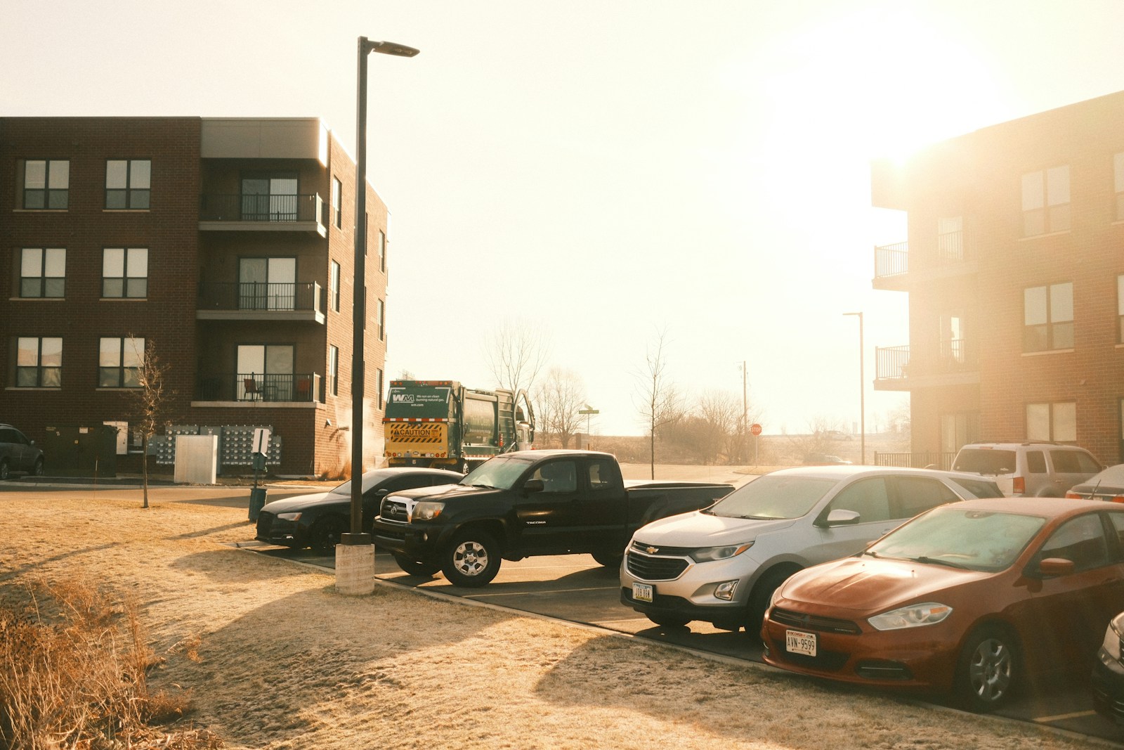 Cars parked in a lot next to apartment buildings.